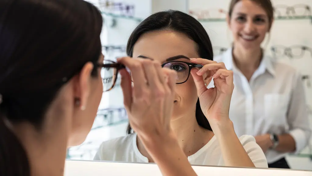 Cliente essayant des lunettes de soleil devant miroir avec opticien conseil